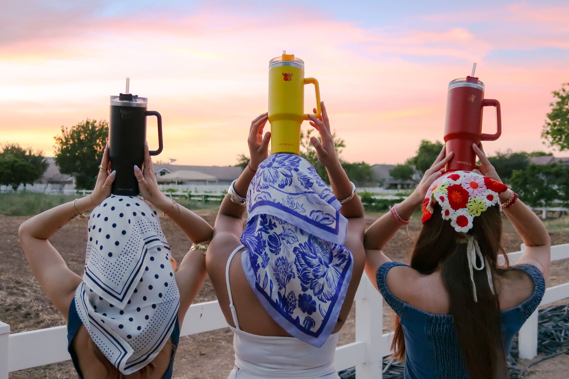 Three Virtue & Co. tumblers raised at sunset